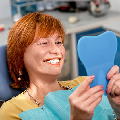 woman examining her smile in a mirror