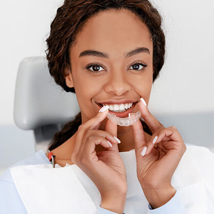 woman holding up a clear aligner